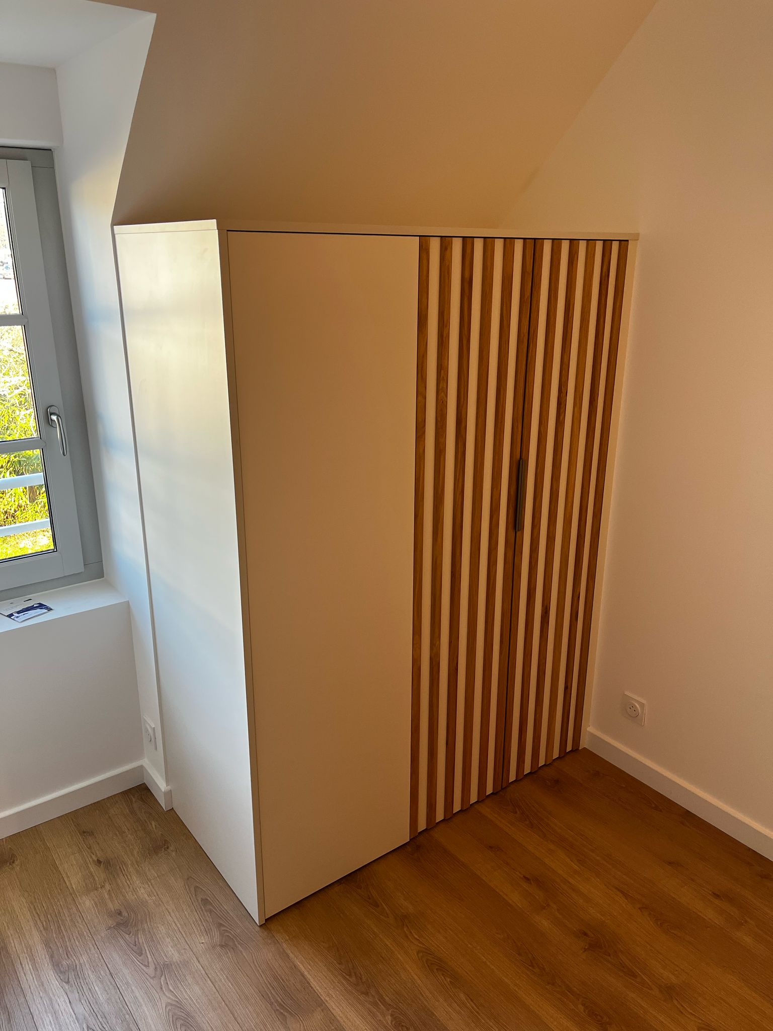 Réalisation sur mesure à Dinard, d'un dressing en mélaminé blanc porcelaine avec lames en chêne sur les portes. par Hugo Pauchard - HP Bois Menuiserie - Saint-Malo