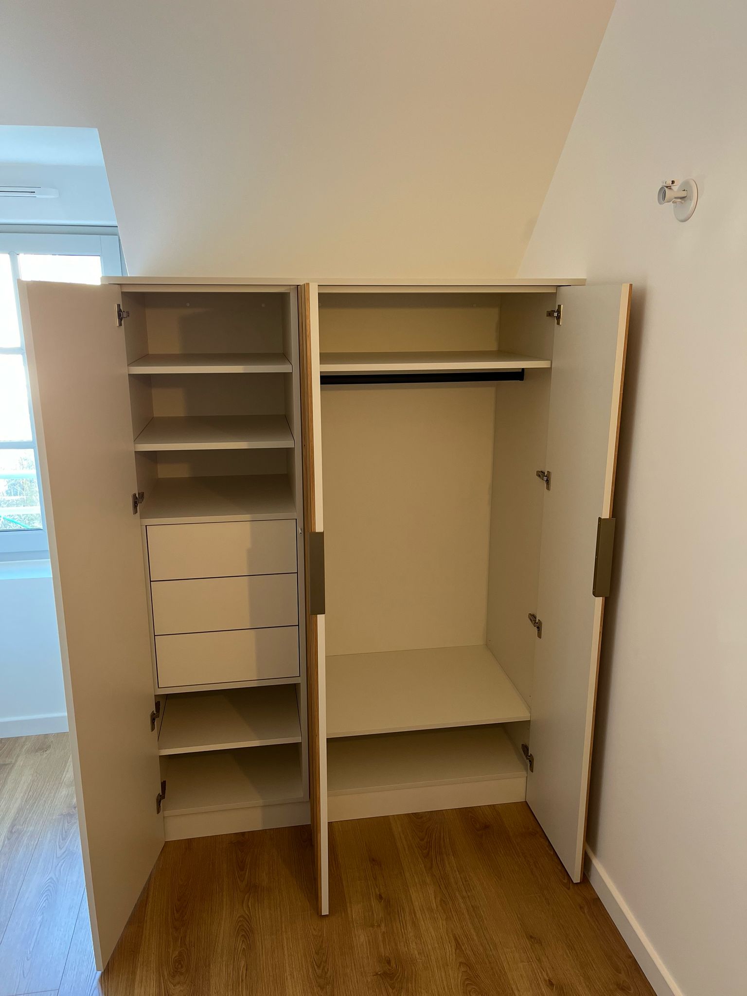 Réalisation sur mesure à Dinard, d'un dressing en mélaminé blanc porcelaine avec lames en chêne sur les portes. par Hugo Pauchard - HP Bois Menuiserie - Saint-Malo