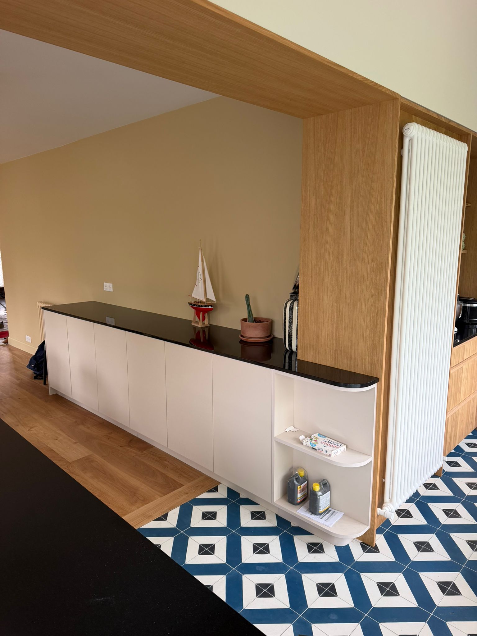 Nouvelle réalisation d'une cuisine sur mesure près de Saint-Malo, pensée pour conjuguer l'authenticité du bois et la modernité des touches de noir et de carrelage géométrique. Ses espaces dédiés et son ouverture sur l’extérieur en font un lieu de vie aussi pratique qu'esthétique au quotidien. - CCM Agencement - Saint-Malo