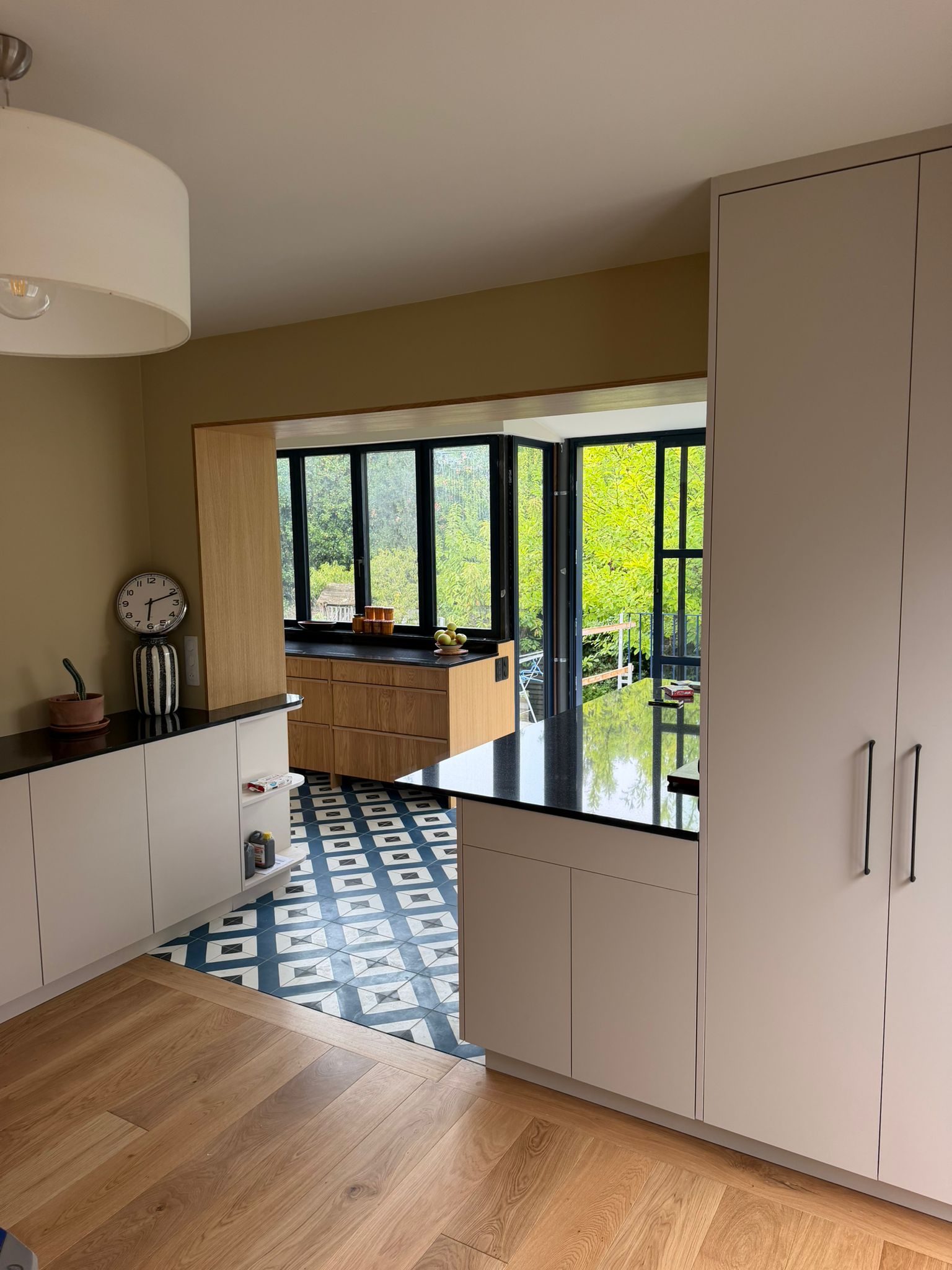 Nouvelle réalisation d'une cuisine sur mesure près de Saint-Malo, pensée pour conjuguer l'authenticité du bois et la modernité des touches de noir et de carrelage géométrique. Ses espaces dédiés et son ouverture sur l’extérieur en font un lieu de vie aussi pratique qu'esthétique au quotidien. - CCM Agencement - Saint-Malo